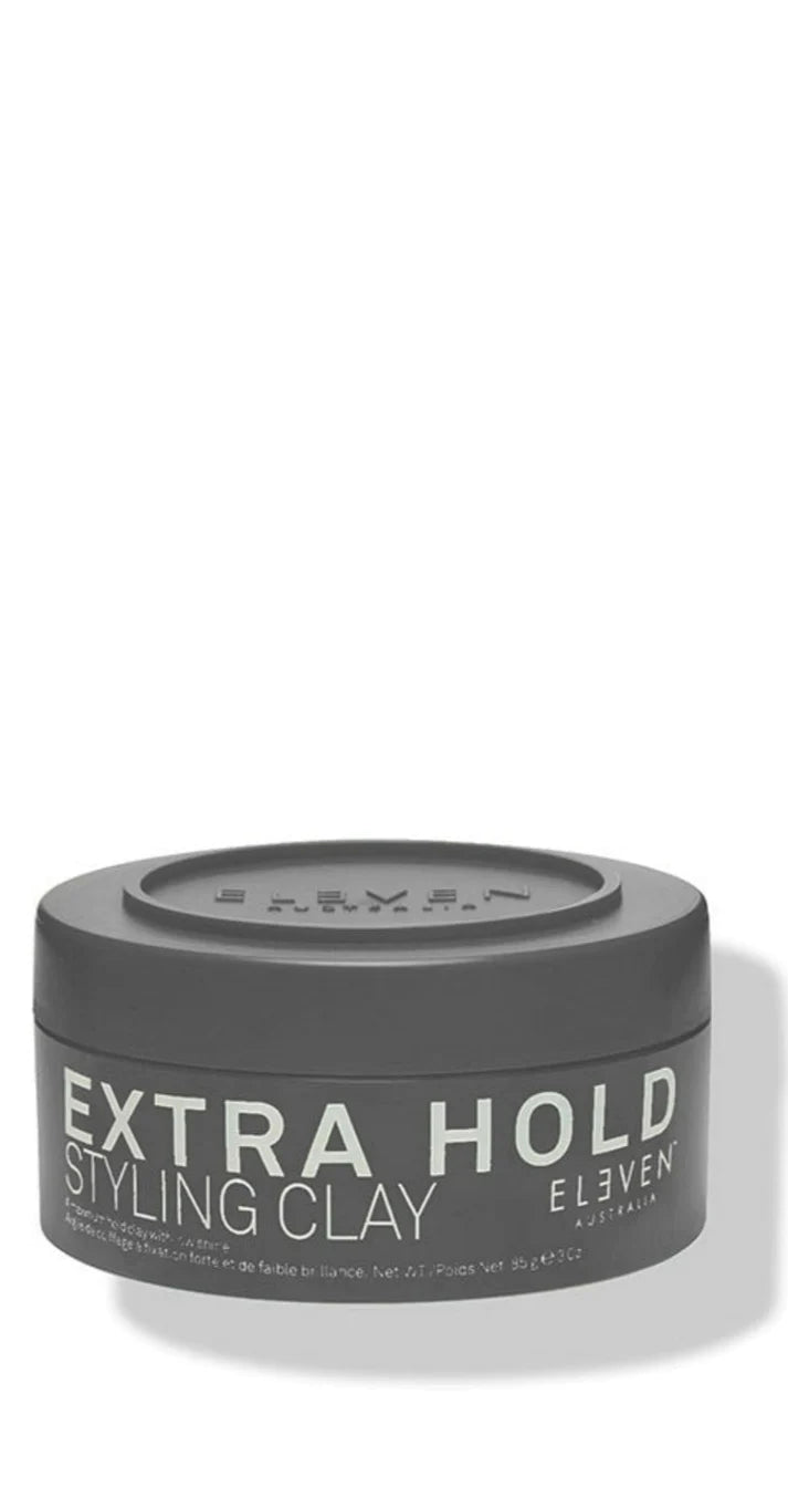 A gray container of Extra Hold Styling Clay with text on it, indicating the product is designed for 24-hour hold and matte look. By ELEVEN.