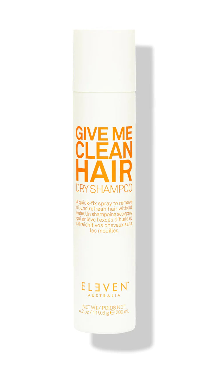 A bottle of ELEVEN brand 'Give Me Clean Hair' dry shampoo with white and orange labeling.