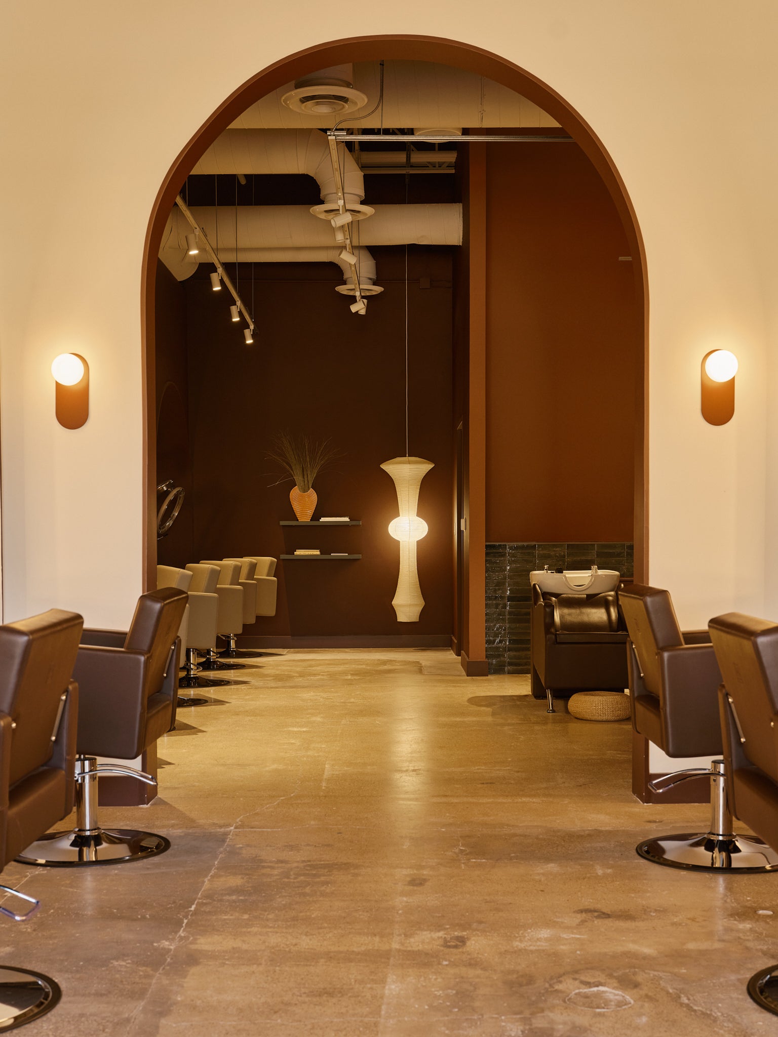 Inside Revel Workshop at the client stations with an arched wall and the warm glow of a hanging lamp