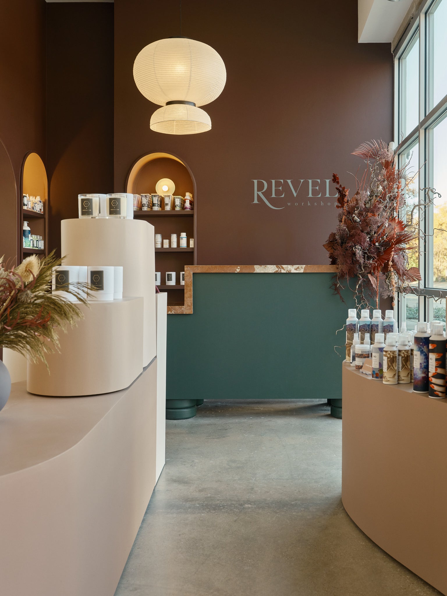 Interior view of Revel Workshop with retail products on smooth curved shelves and a curvy light overhead