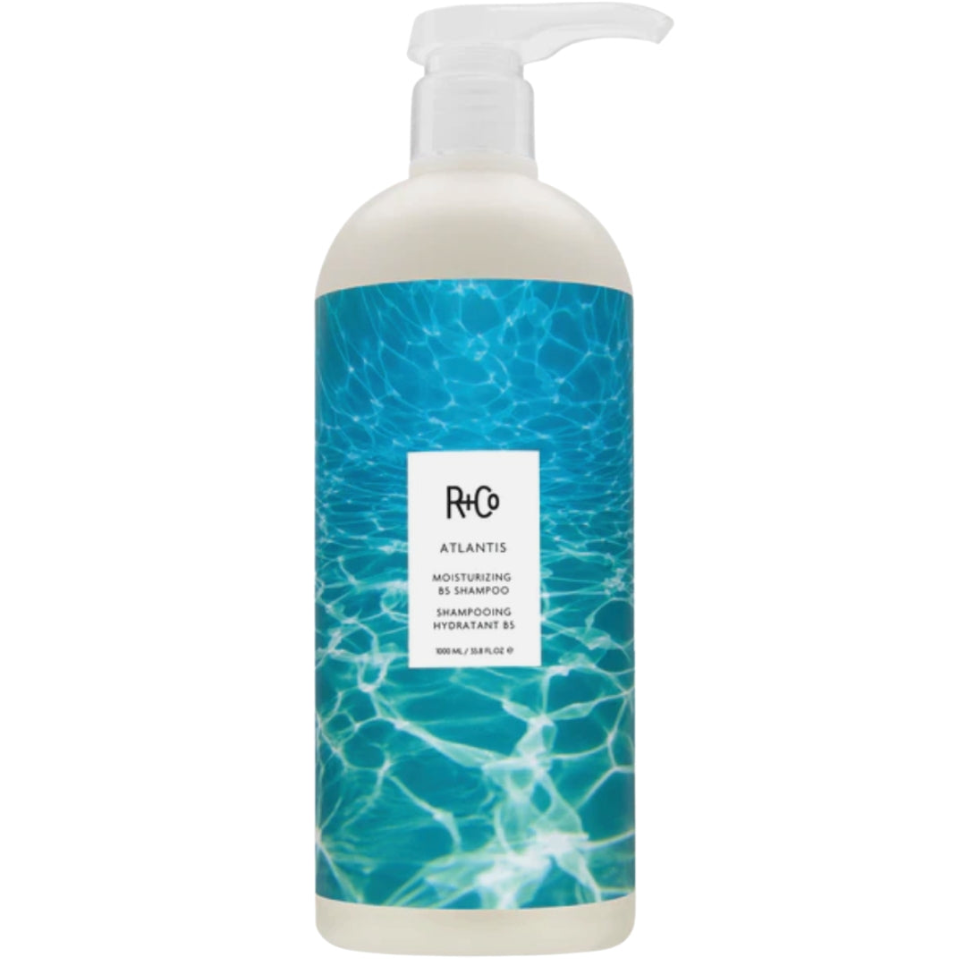 Bottle of R+Co ATLANTIS Moisturizing Shampoo with blue label design and pump dispenser