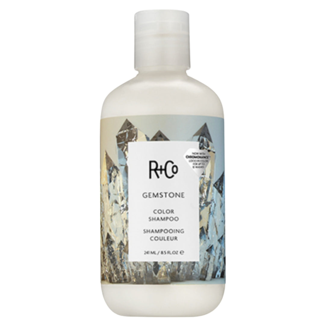 A bottle of R+Co Gemstone Color Shampoo with a label featuring an image of crystals.