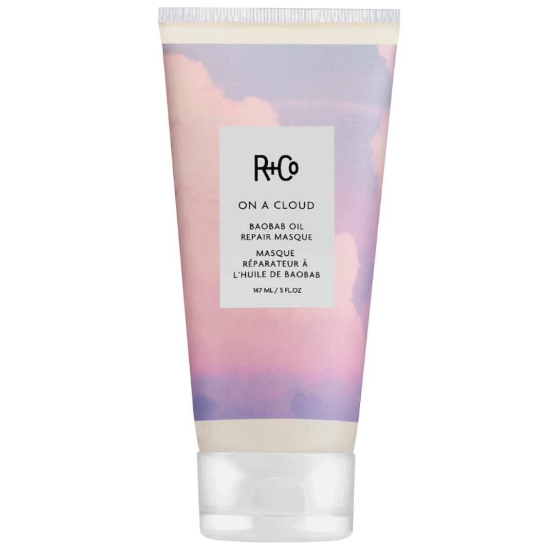 A tube of R+Co On a Cloud Repair Masque with a purple and pink cloud design on the label.