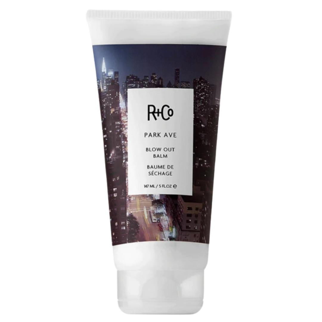 White container of R+Co Park Ave Blow Out Balm hair product with picture of big city on label