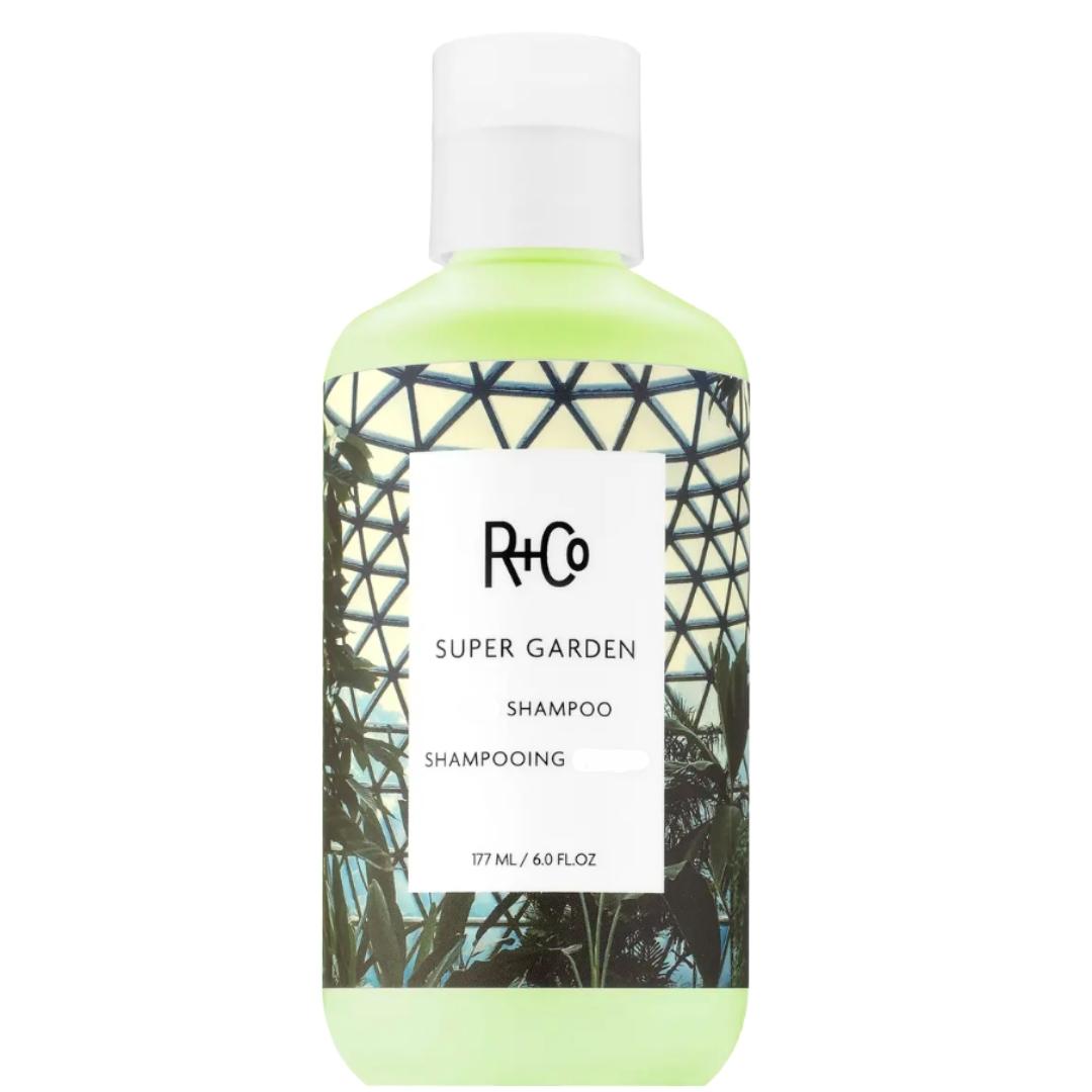 A bottle of R+Co Super Garden Shampoo hair product with a greenish hue and geometric patterns on the label.