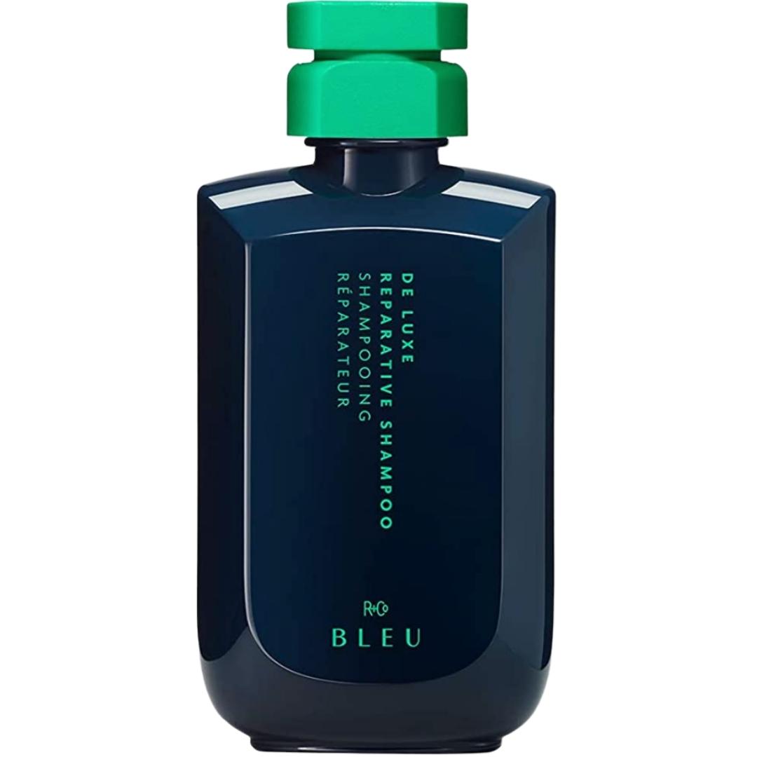Blue bottle with green cap; De Luxe Reparative Shampoo hair product by R+Co Bleu