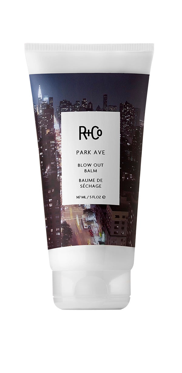 White tube of R+Co Park Ave Blow Out Balm with image of a big city on the label