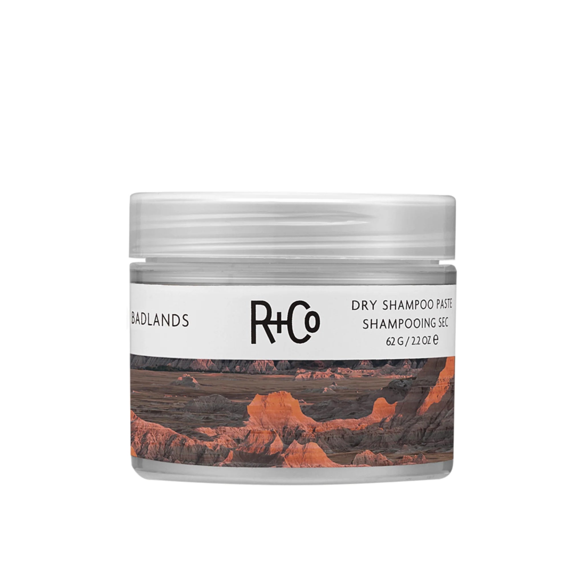 A container of R+Co Badlands Dry Shampoo Paste with a label featuring a landscape image.