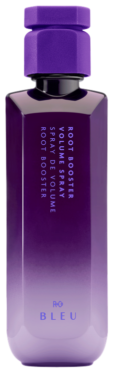 A bottle of R+Co BLEU Root Booster Volume Spray with a purple cap and a label that includes the product name and the word 'bleu'.
