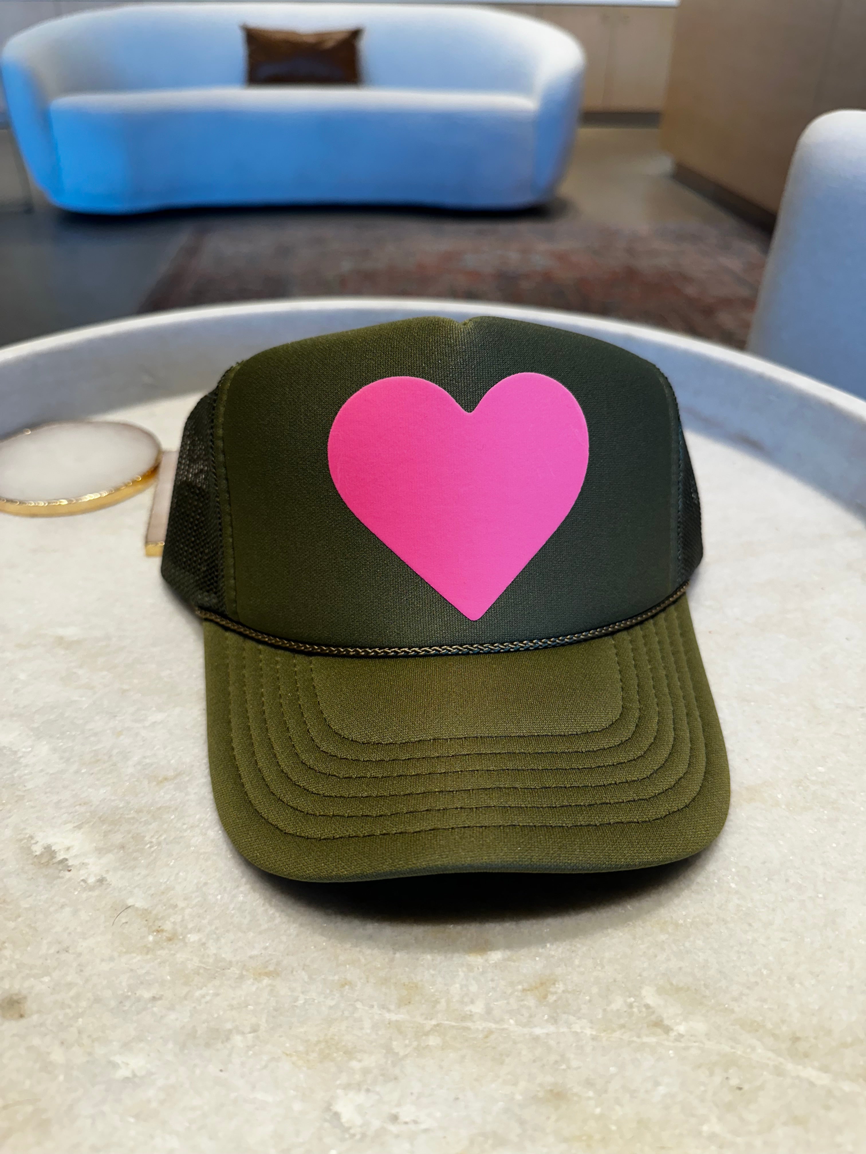 Green trucker hat with large pink heart logo on the front