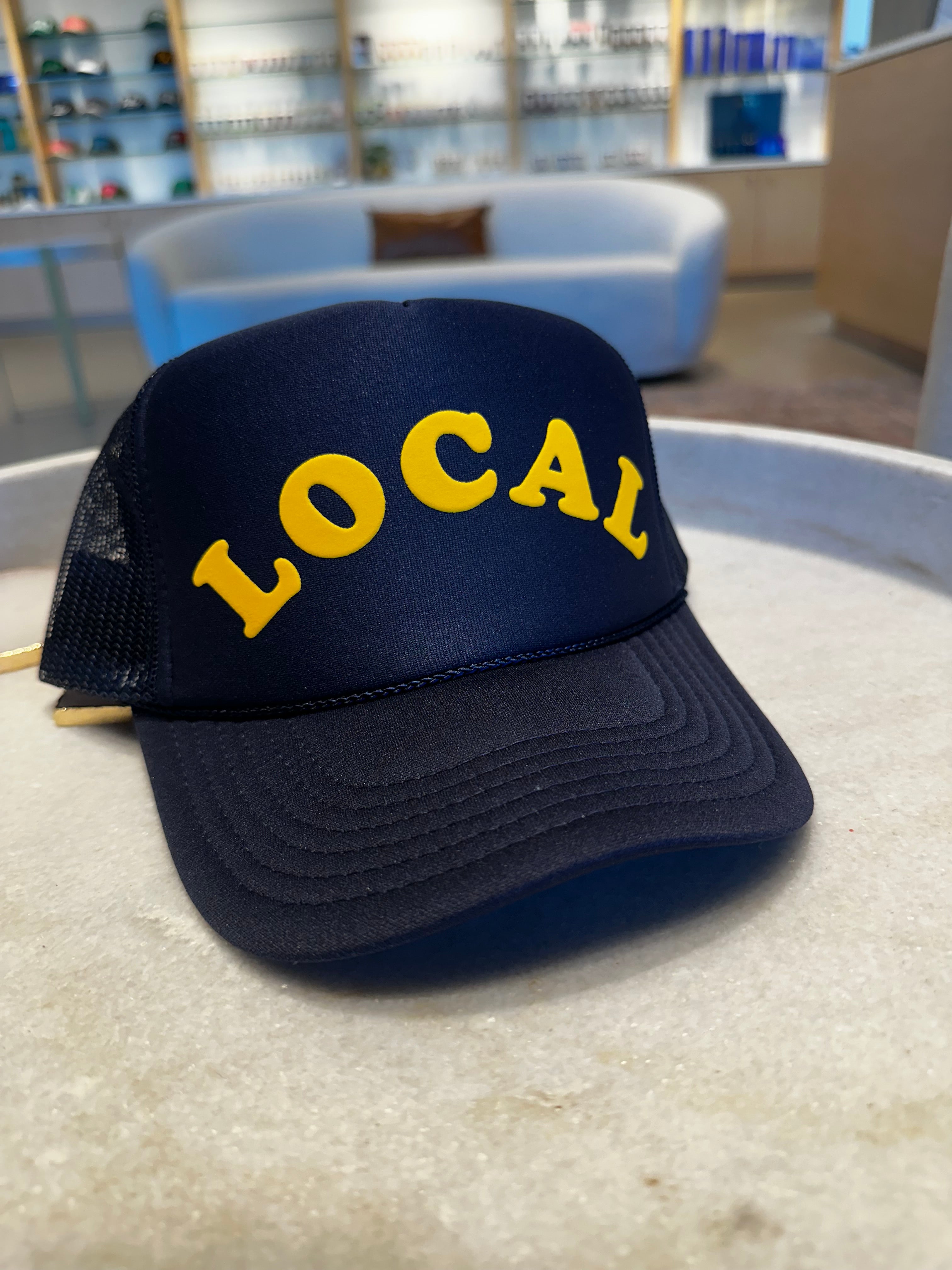 Dark blue trucker hat with the word 'LOCAL' on the front in yellow letters