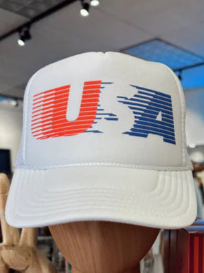 White trucker hat with 'USA' design on a wooden mannequin head in a store setting.