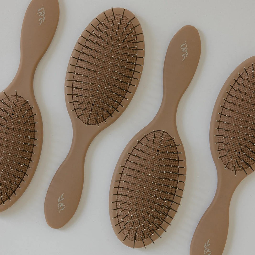 Set of four brown Willow detangling hairbrushes with visible brand logo on a light background