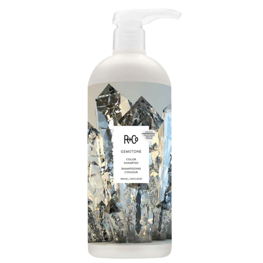 A bottle of R+Co Gemstone Color Shampoo with a label featuring an image of crystals.