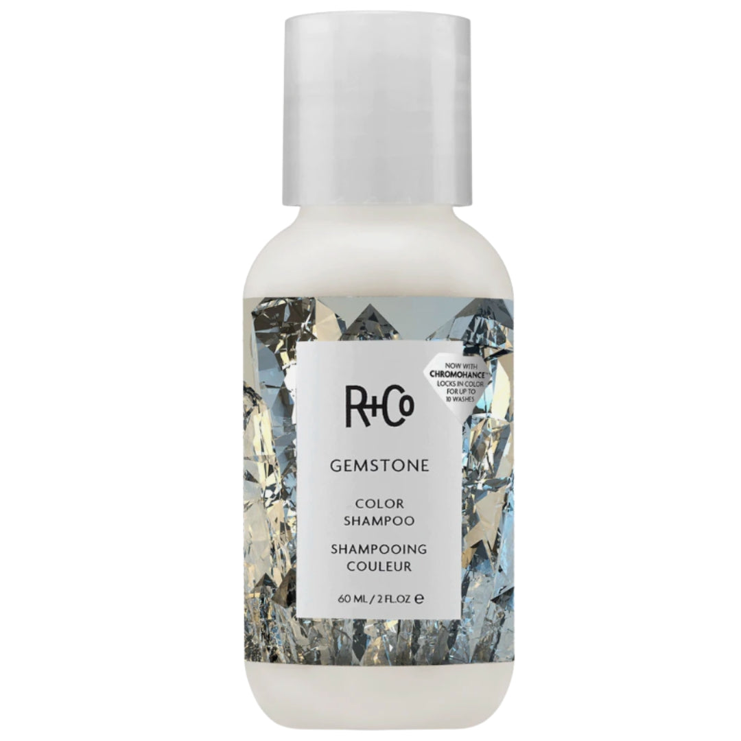 A travel size bottle of R+Co Gemstone Color Shampoo with a label featuring an image of crystals.