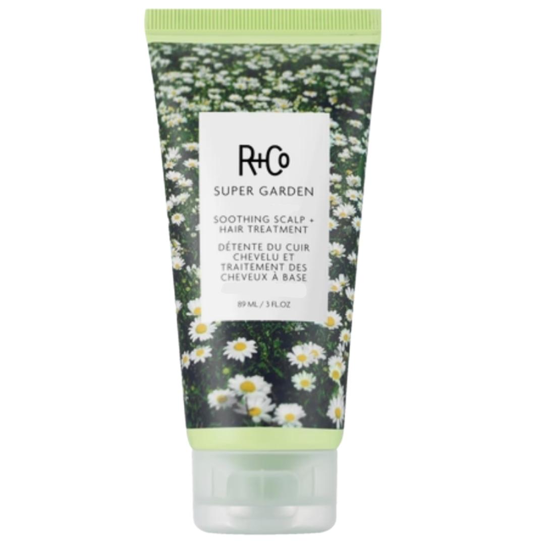Tube of R+Co Super Garden Soothing Scalp + Hair Treatment product with a design of white flowers with yellow centers.