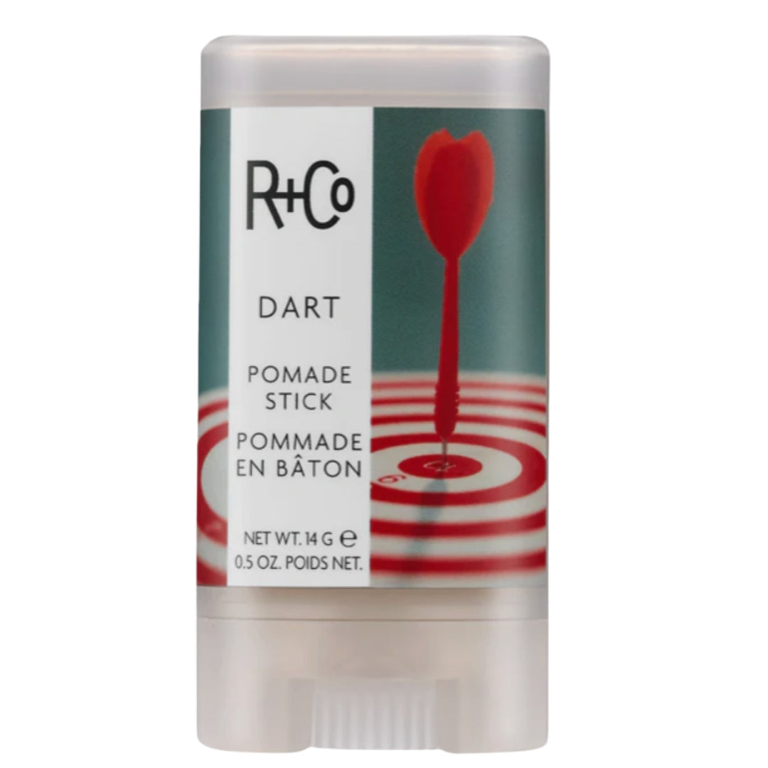 A pomade stick with a white and green label, featuring a red dart in the center that indicates the product name 'DART' by R+Co.